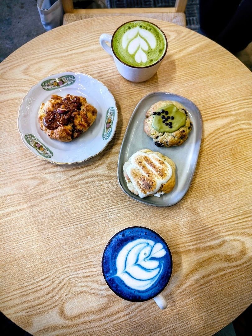 Vue de dessus : matcha latte au dessin de feuille et blue matcha au butterfly pea, avec des cookies sur des assiettes.