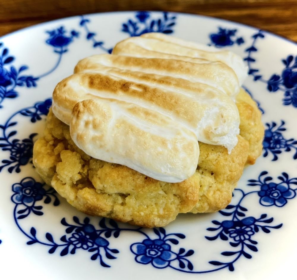 Gros plan sur un cookie coiffé de meringue toastée, posé sur une assiette fleurie bleu et blanc.