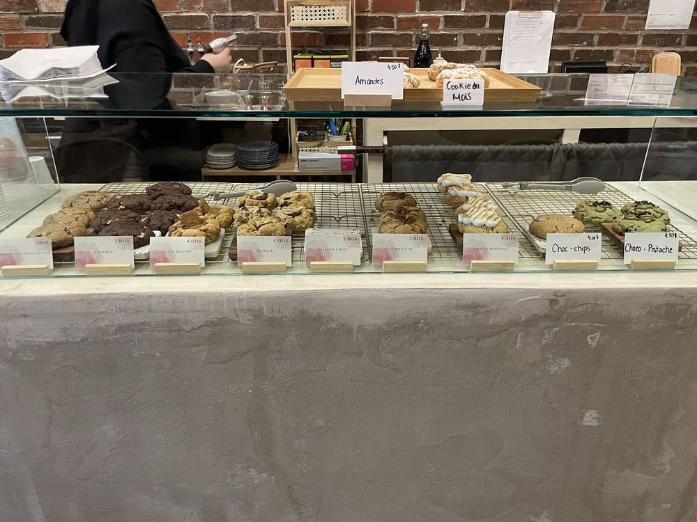 Vitrine de cookies maison avec petites étiquettes de prix, devant le mur de brique.