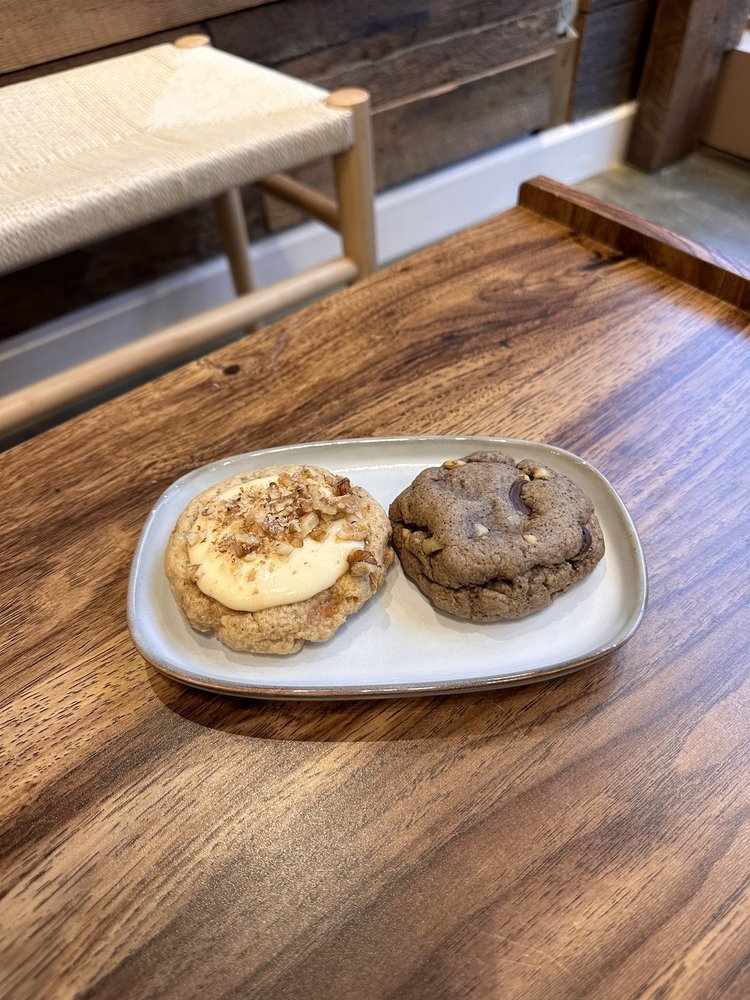 Deux cookies maison, l'un garni de crème et l'autre double chocolat, sur une assiette en grès.