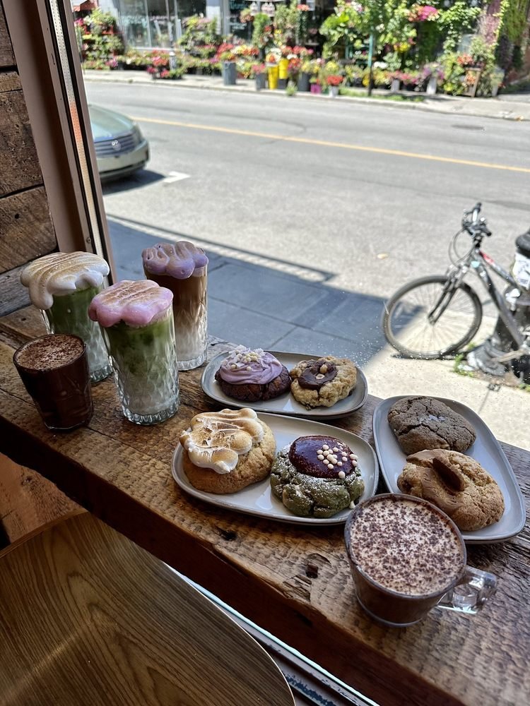 Rebord de fenêtre garni de cloud lattes et d'un assortiment de cookies, boutique de fleurs de la rue Bernard en arrière-plan.